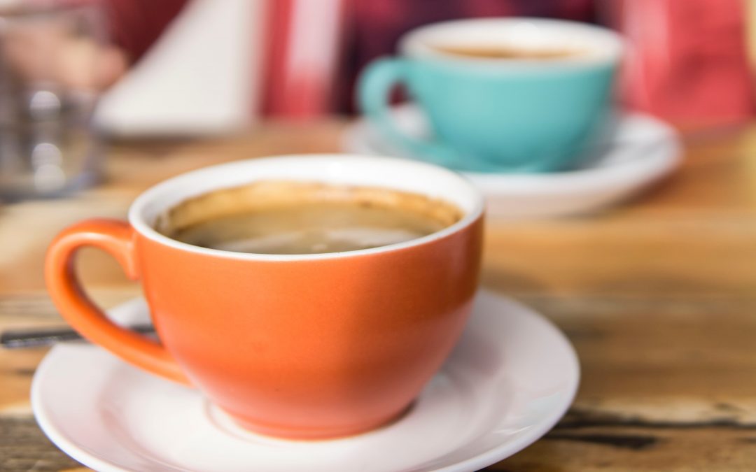 Dos tazas de café una de coler calabaza en primer plano y otra al fondo de color turquesa